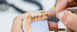 A dental technician working on a dental bridge