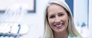 A middle-aged woman smiling in a dental office