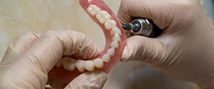 Lab technician filing dentures