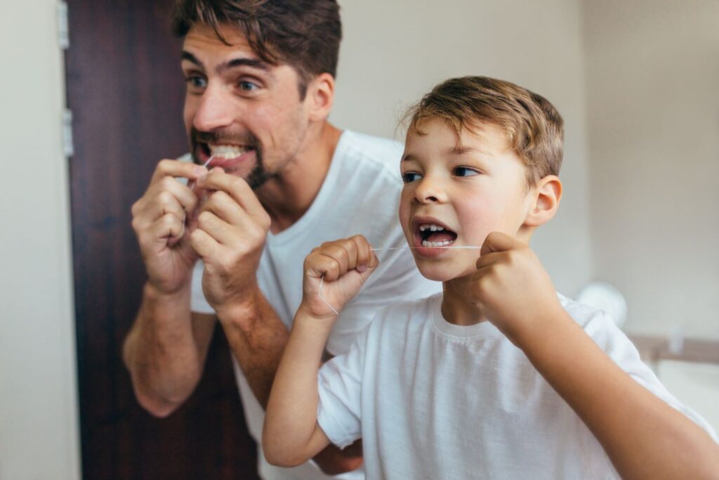 A father and son flossing their teeth.